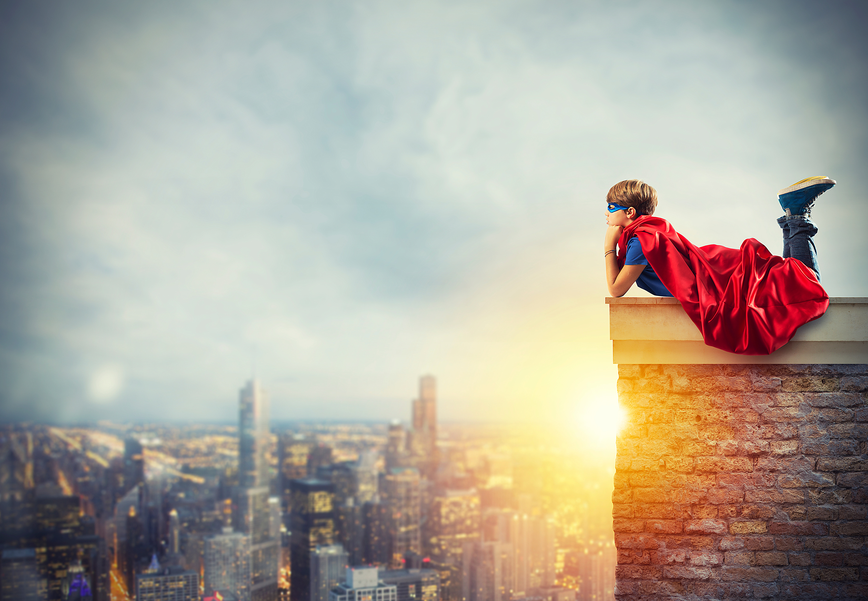 Superhero kid sitting on a wall that dreams